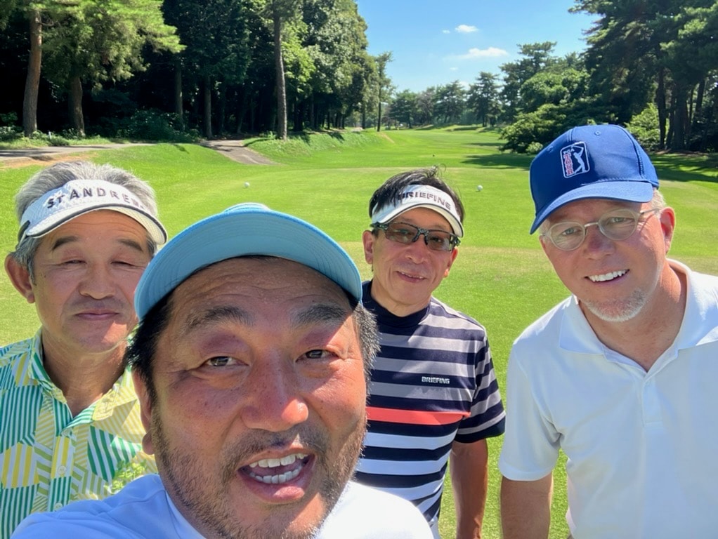 Foursome selfie on a sunny tree-lined Japanese golf course fairway